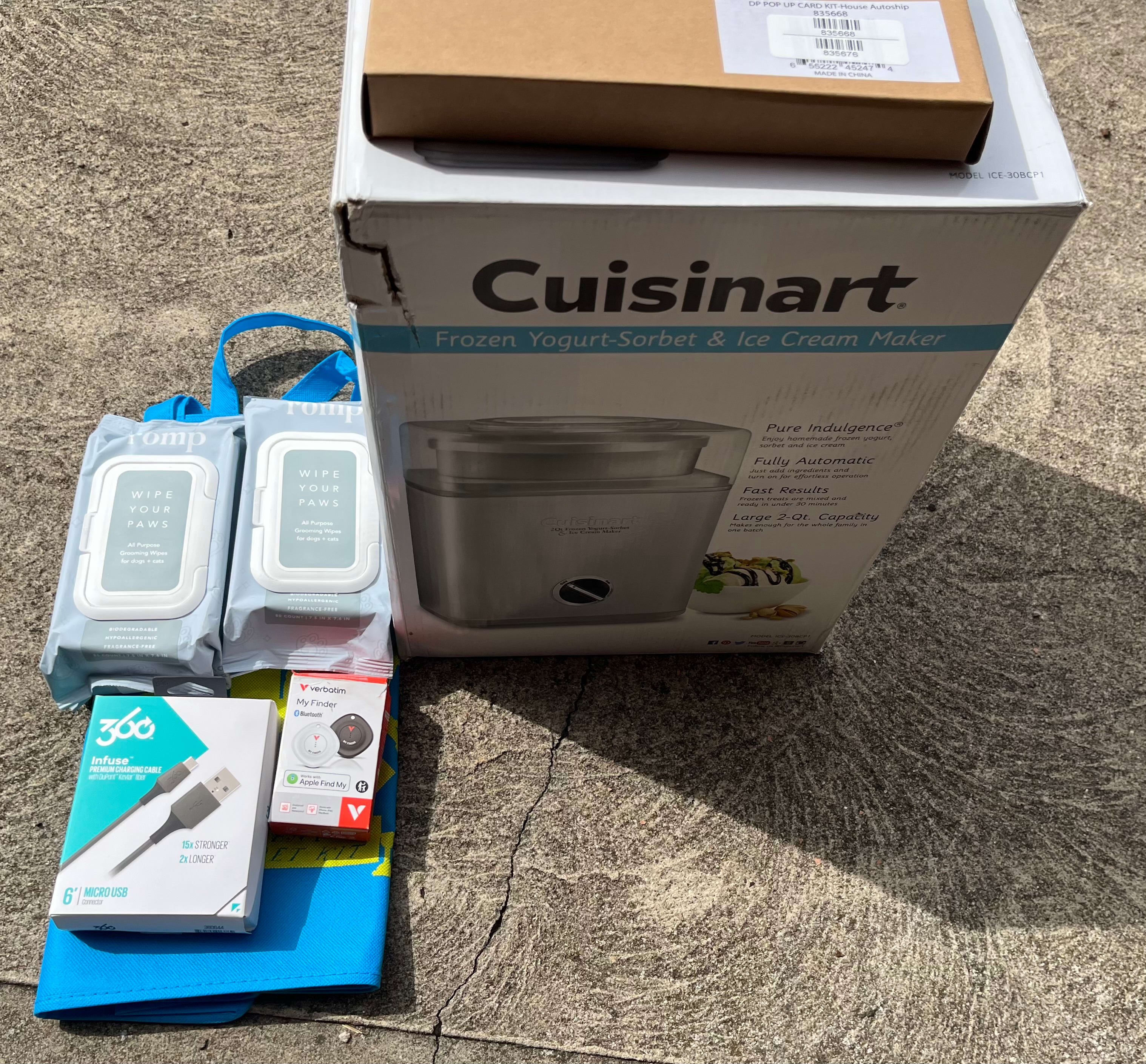 Better than expected, I guess. Light blue IRK bag. Two packages of paw wipes. My cats don't leave the house. A USB cable. A fine backup if my other 42 cables stop working. Off brand apple tracker tags. That brown box has some sort of kit in it. Pop-up House? Looks like the sort of disappointing thing you might give a kid who wanted to go play outside but it's pouring rain. And finally, a really beat up Cuisinart box. I've turned the best side to the camera. Surely that's not got a Cuisinart in it. Huh. It actually does. A frozen yogurt/ sorbet/ice cream maker. I don't actually need it. But I think that one will actually find a home. If it works. The packing inside the box actually seems intact.  